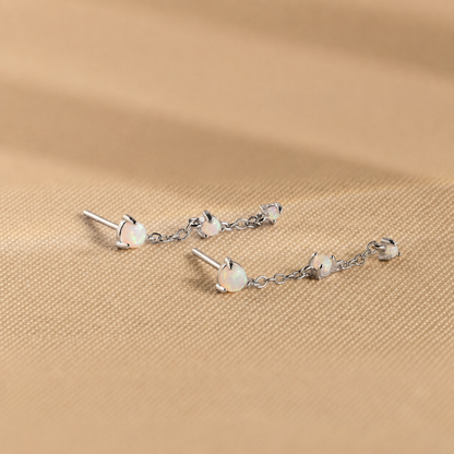 Silver earrings with opal stones on a beige fabric background