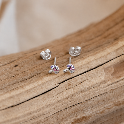 Silver earrings with colorful gemstones on a wooden surface