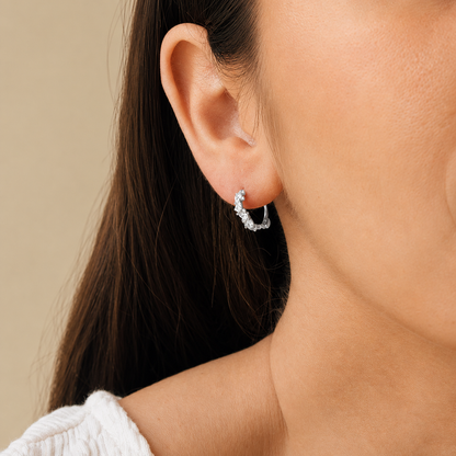 Close-up of a woman wearing a silver hoop earring against a neutral background