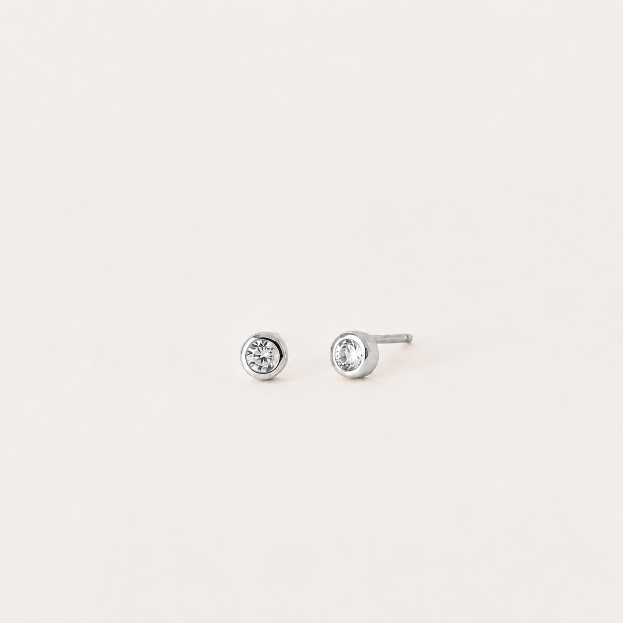 Pair of silver stud earrings with clear gemstones on a light gray background