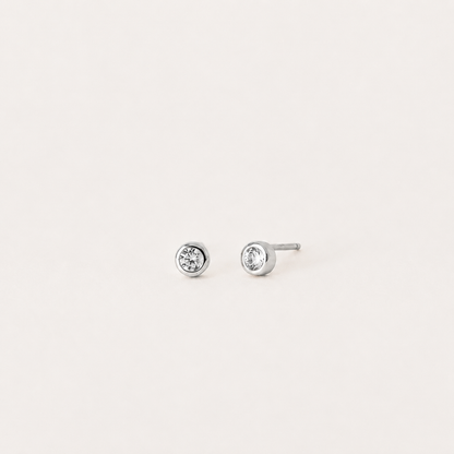Pair of silver stud earrings with clear gemstones on a light gray background