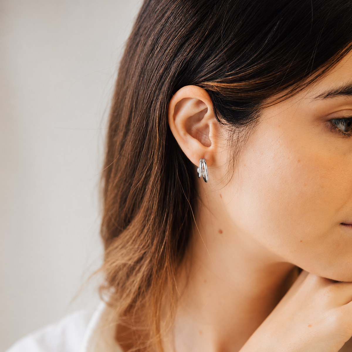 Close-up of a woman wearing a silver earring with a neutral background