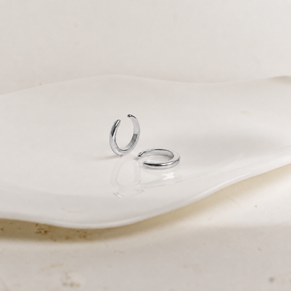 Two silver hoop earrings on a white ceramic plate