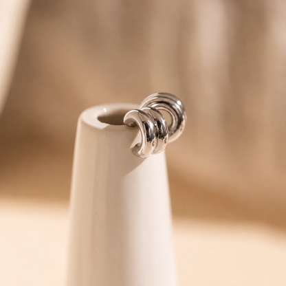 Close-up of a silver ring on a white ceramic vase against a blurred beige background