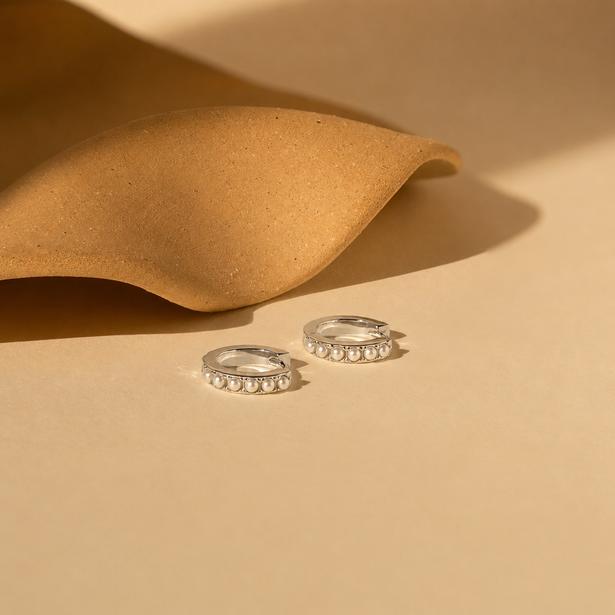 Two silver rings with beaded details on a beige surface