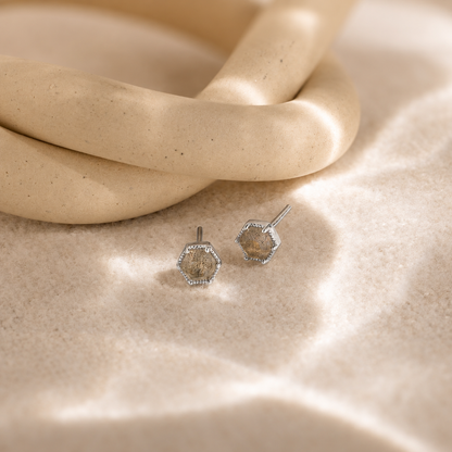 Hexagonal earrings on a textured beige surface