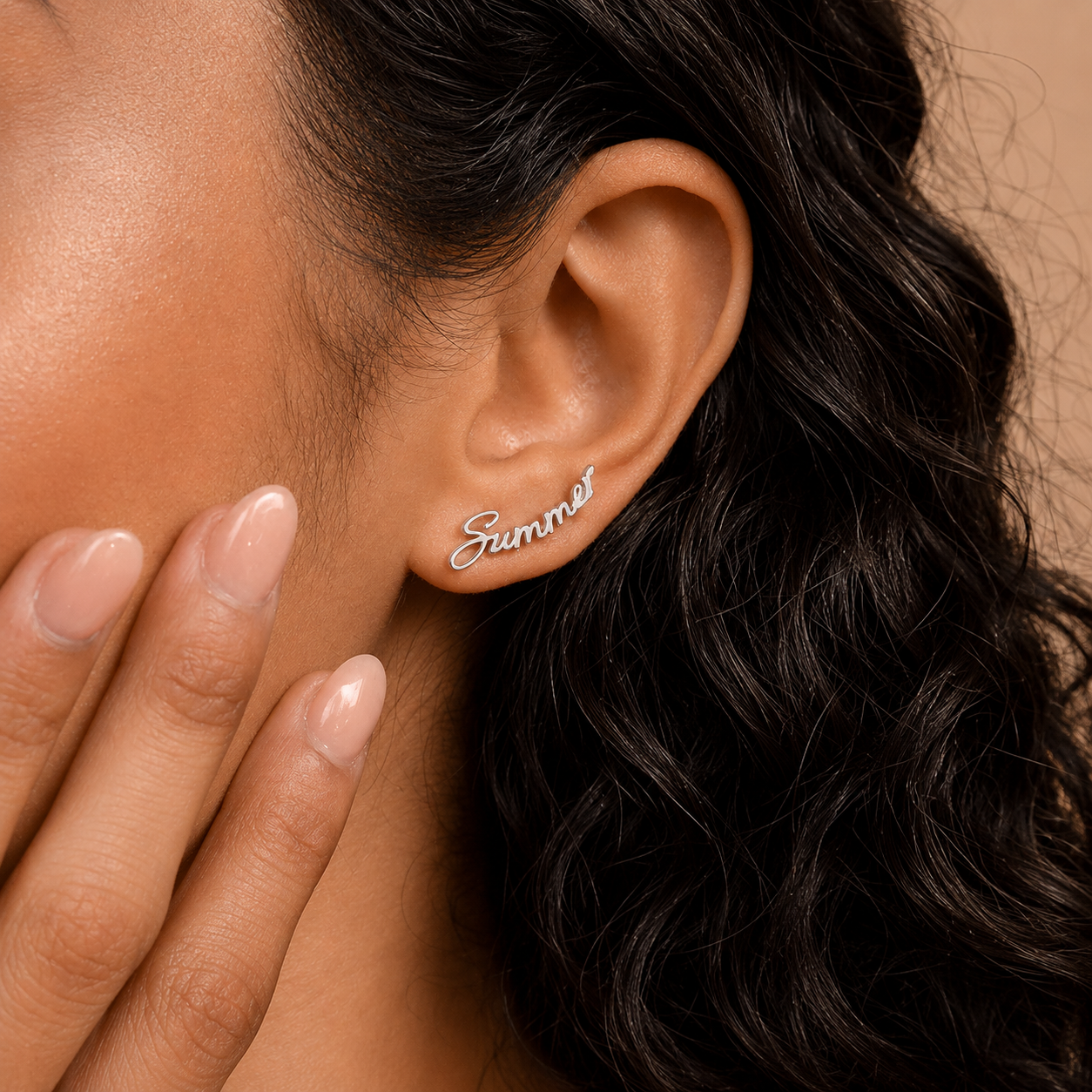 Close-up of an ear wearing a 'Summer' earring with a hand touching the cheek.