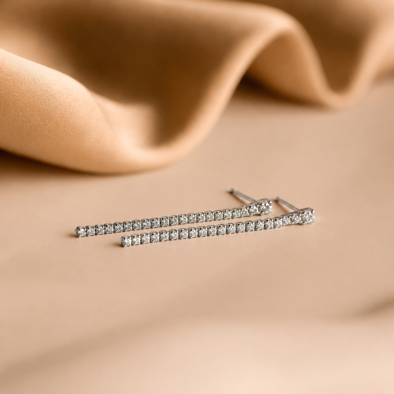 Pair of diamond stud earrings on a beige fabric background