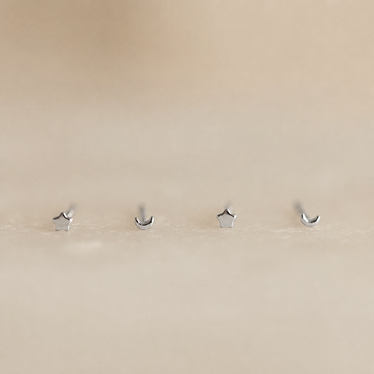 Four silver hooks on a beige wall