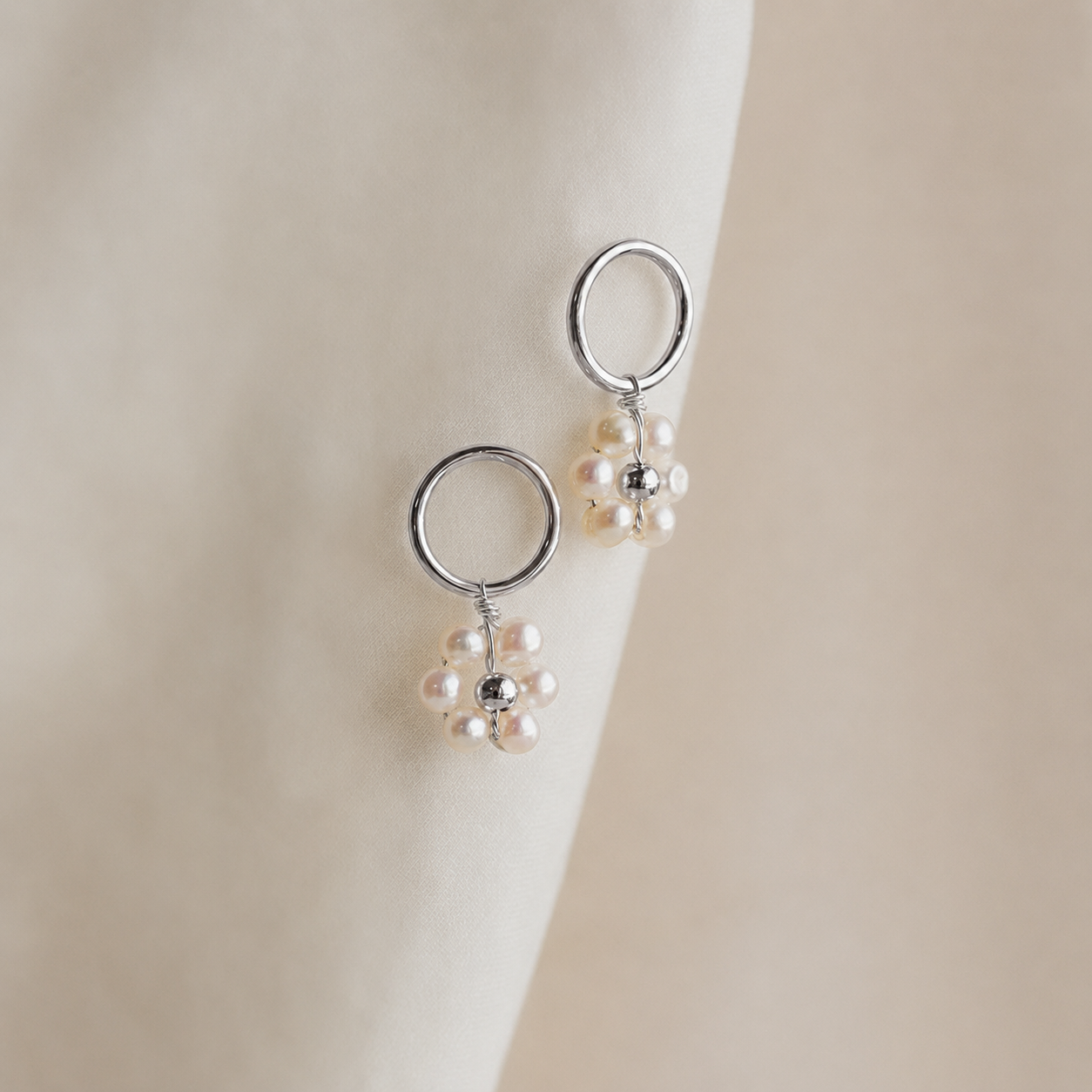 Silver earrings with pearl drops on a neutral background