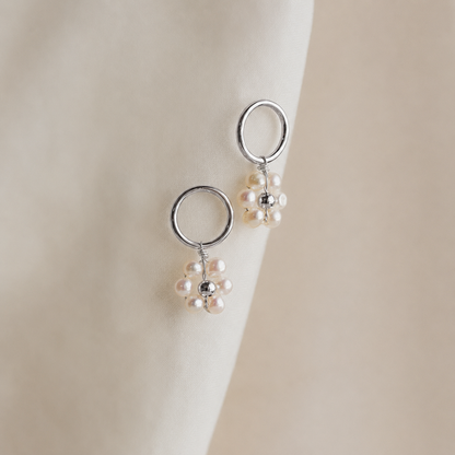 Silver earrings with pearl drops on a neutral background