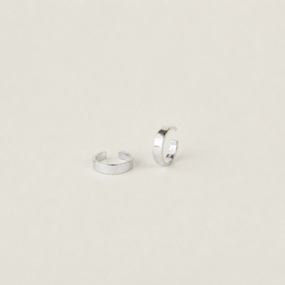 Two silver hoop earrings on a light beige background