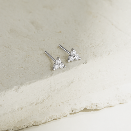 Silver triangle-shaped stud earrings on a light stone surface