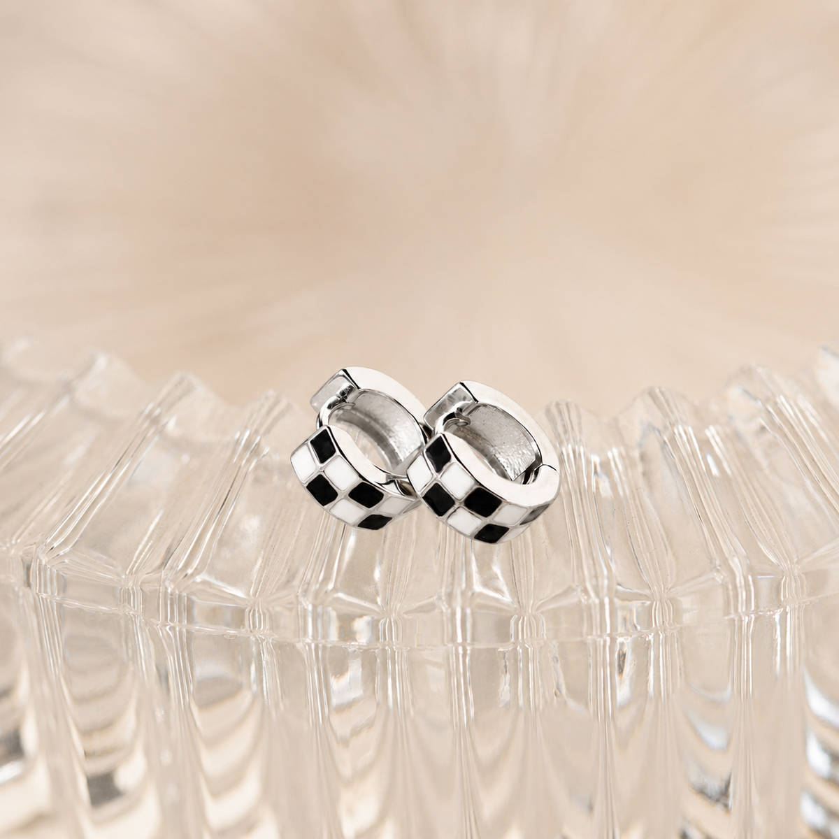 Silver hoop earrings on a clear stand with a beige background