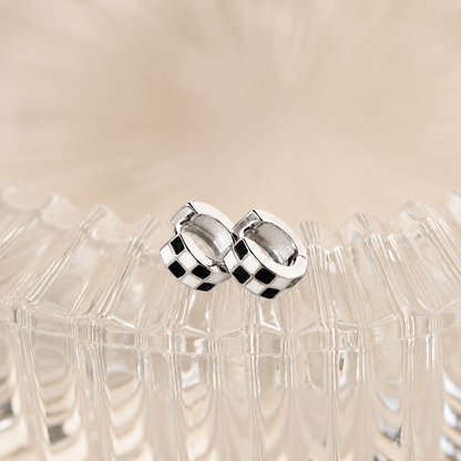 Silver hoop earrings on a clear stand with a beige background