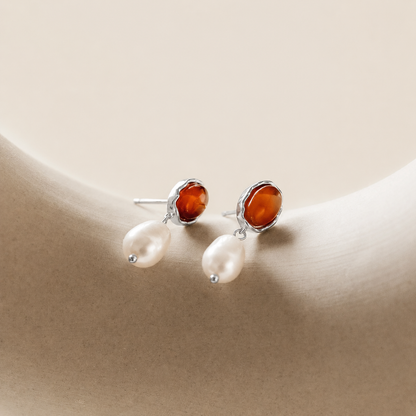 Pair of earrings with amber stones and pearls on a beige background