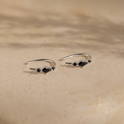 Two silver rings with black gemstones on a beige surface