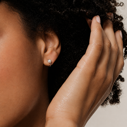 Close-up of a person's hand touching their hair with a neutral background