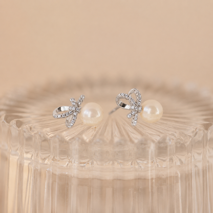 Pair of silver earrings with pearls on a beige background