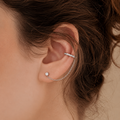 Close-up of an ear wearing a silver earring with a blurred background