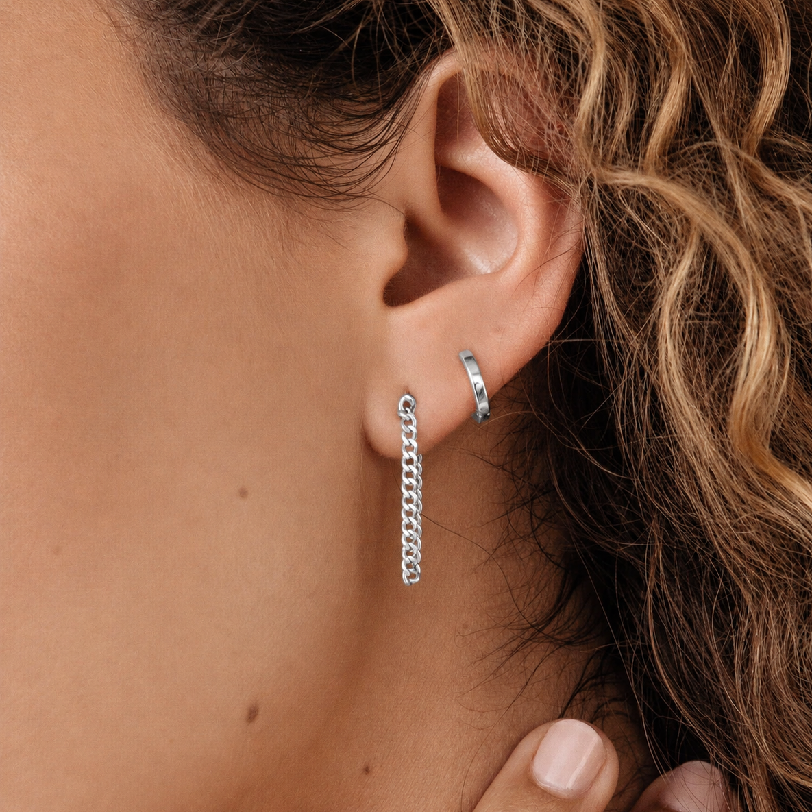 Close-up of a person wearing silver hoop earrings with a blurred background