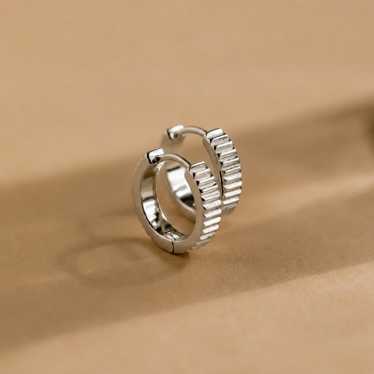 Silver hoop earrings on a beige background