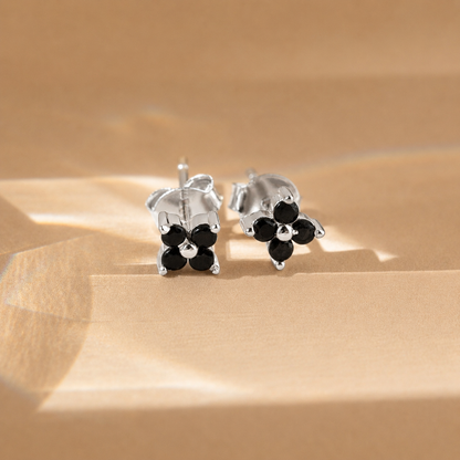 Silver earrings with black stones on a beige surface