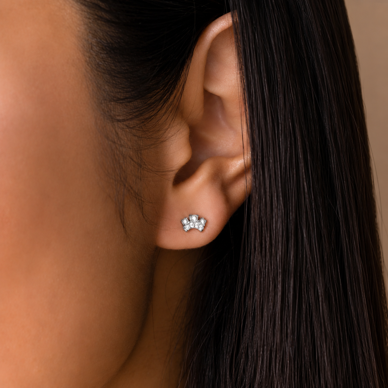Close-up of an ear wearing a diamond earring with hair partially covering the face.