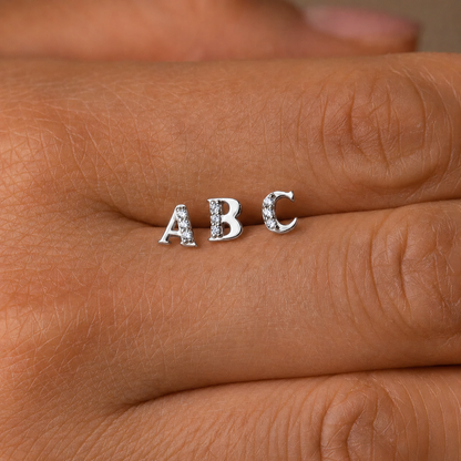 Silver 'ABC' earrings on a person's hand