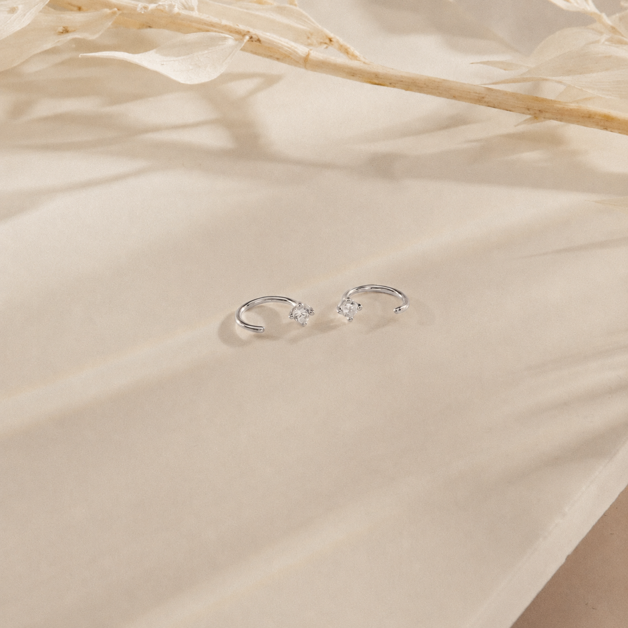 Silver earrings on a beige fabric background