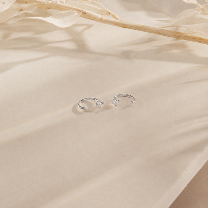 Silver earrings on a beige fabric background