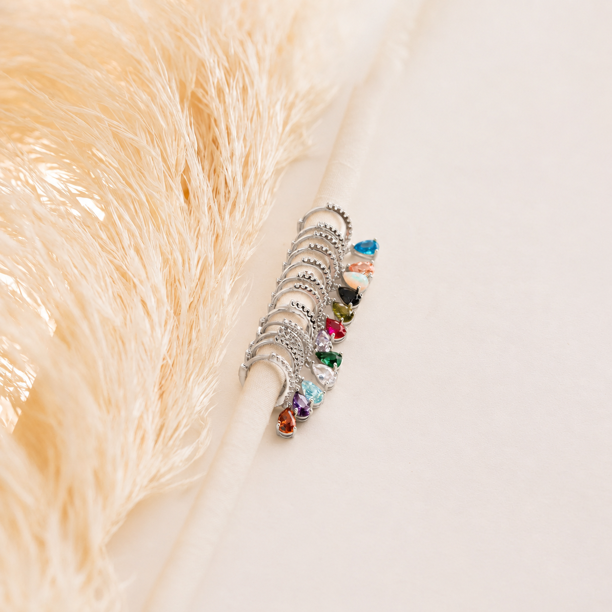 Set of silver rings with multicolored gemstones on a textured beige surface