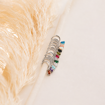 Set of silver rings with multicolored gemstones on a textured beige surface