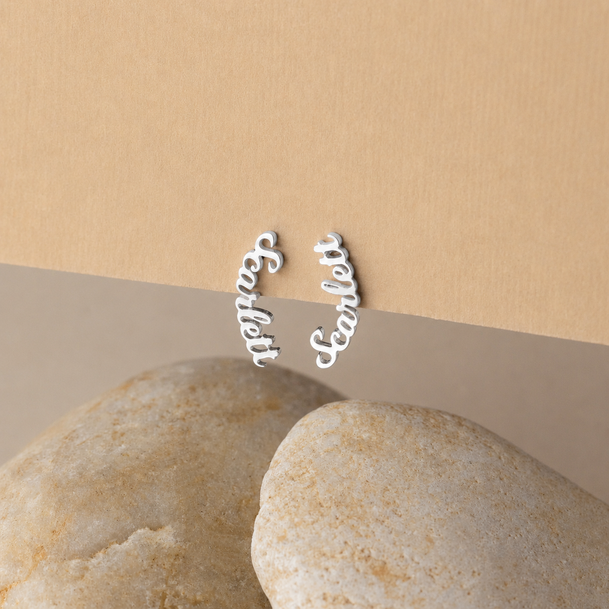 Silver 'Sister' and 'BFF' earrings on a beige background