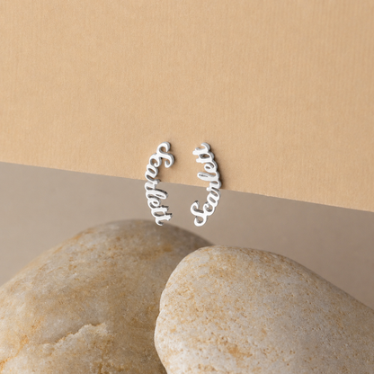 Silver 'Sister' and 'BFF' earrings on a beige background