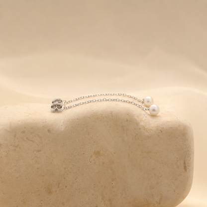 Silver necklace with pearls on a beige stone surface