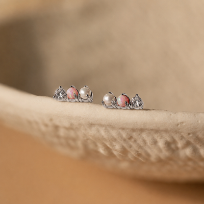 Pair of silver earrings with pink gemstones on a beige surface