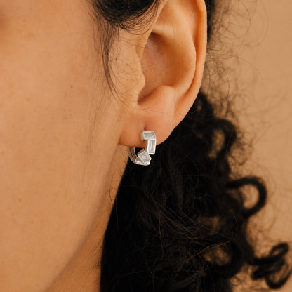 Close-up of an ear wearing a silver hoop earring with a blurred background