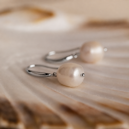Pearl earrings on a wooden surface