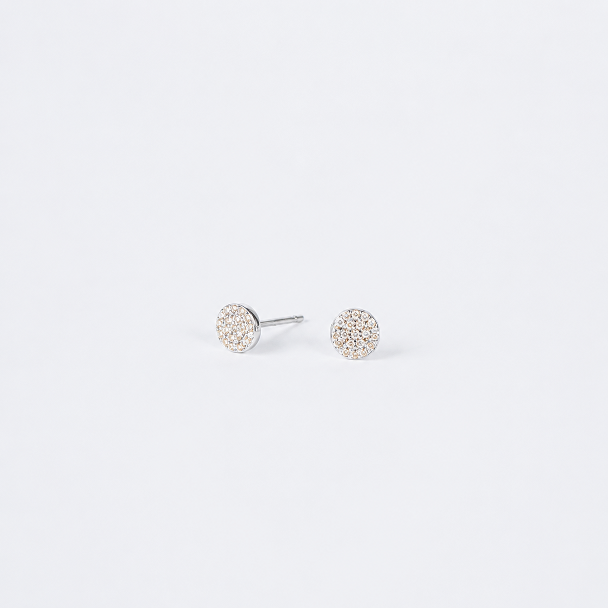A pair of round stud earrings with pavé-set clear stones in a silver-tone setting, shown on a plain light gray background.