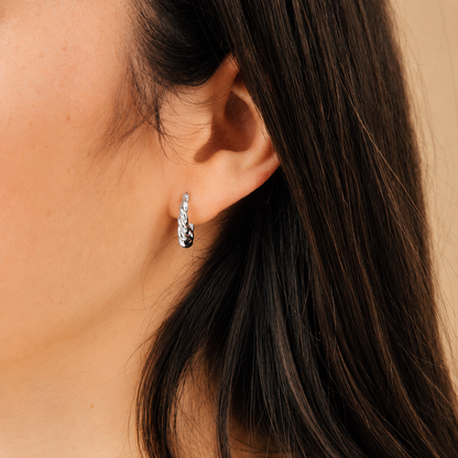 Silver hoop earring worn by a person with dark hair.