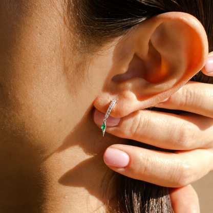 Close-up of an ear with a diamond earring being held by a hand.
