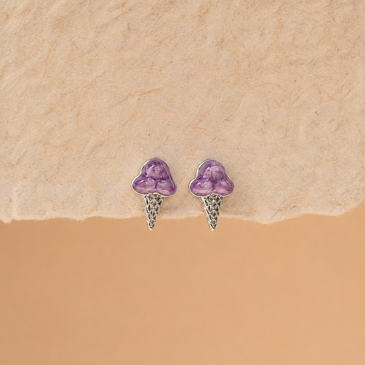 Pair of purple heart-shaped earrings on a beige background