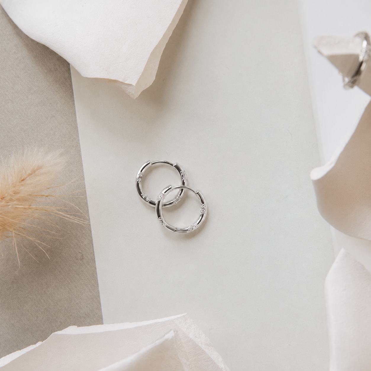 Silver hoop earrings on a soft fabric background