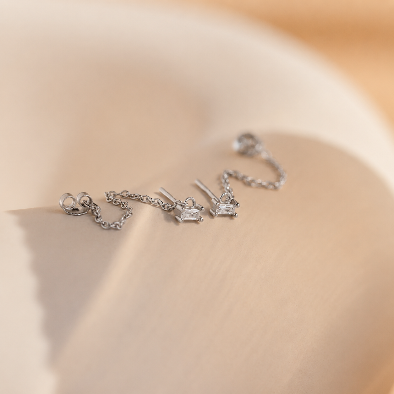 Silver earrings on a beige surface