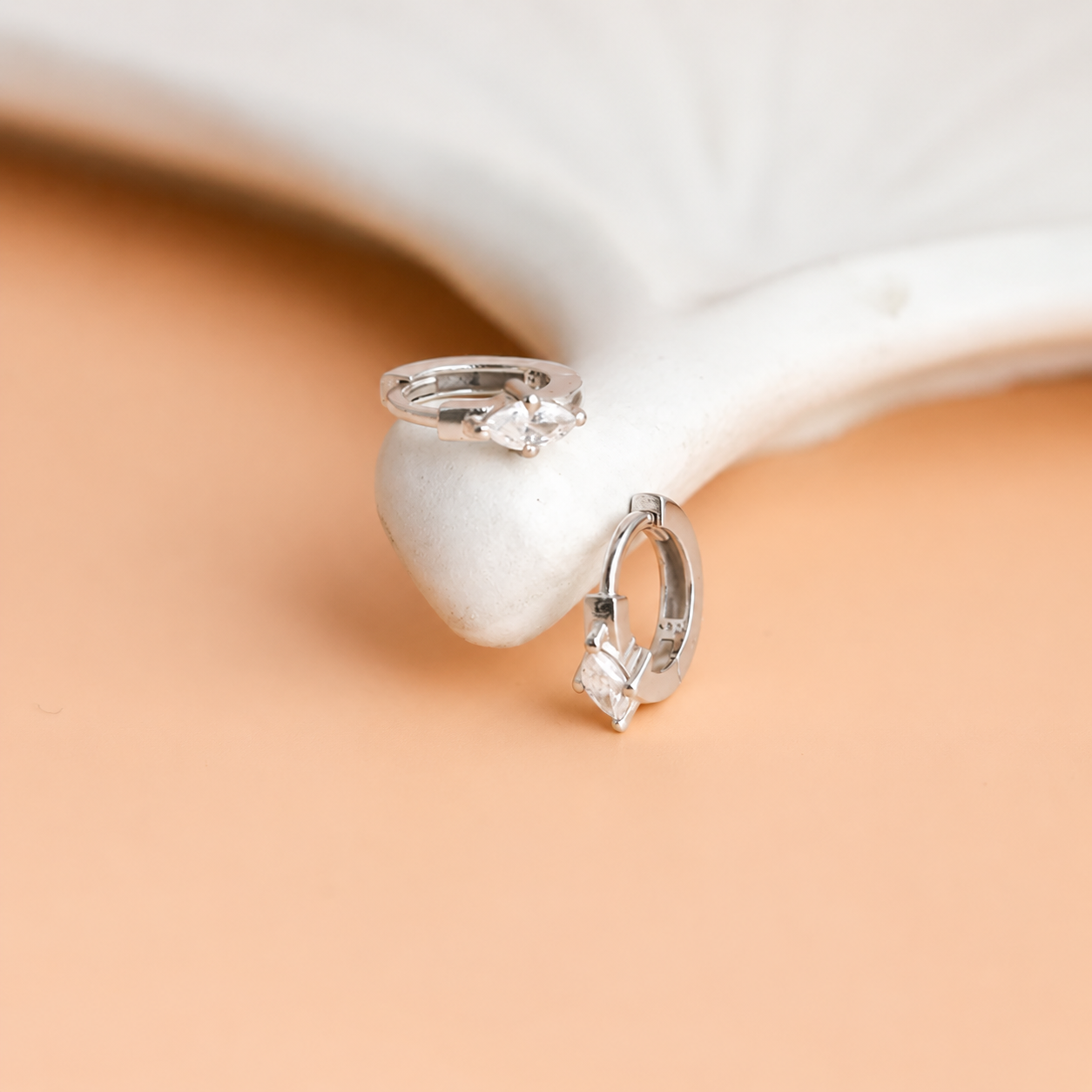 Silver hoop earrings with a pearl on a beige background