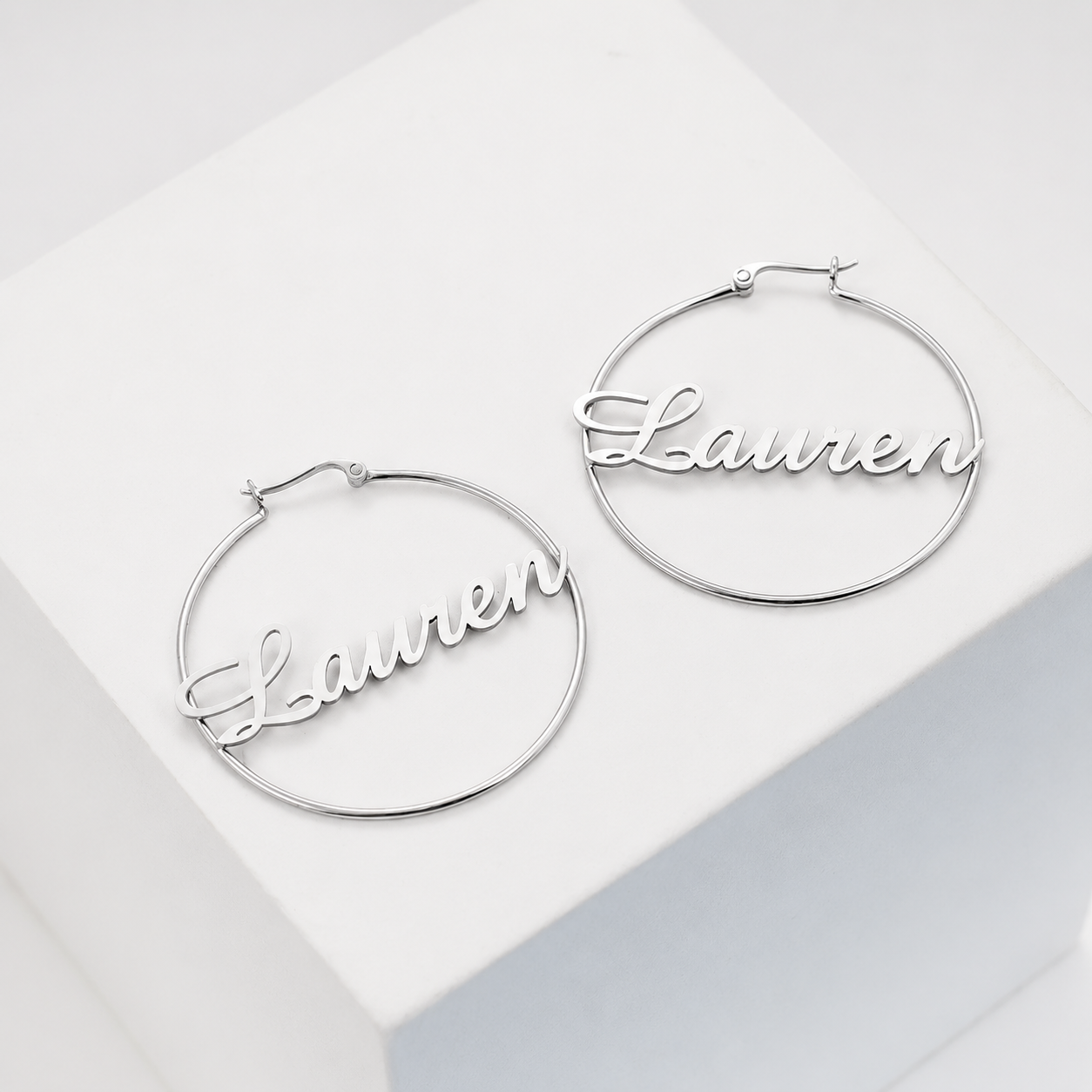 Silver hoop earrings with 'Lauren' engraved on a light gray background