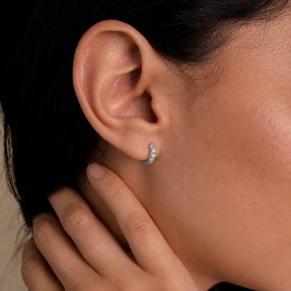 Close-up of an ear with a diamond earring and hand touching hair