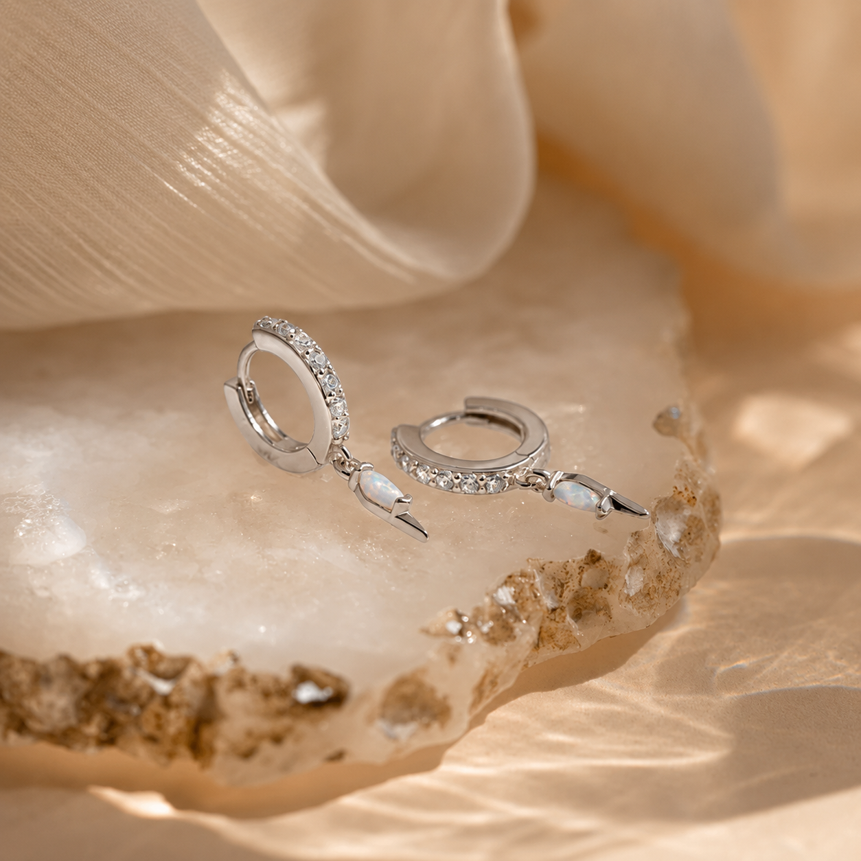 Silver hoop earrings with small stones on a seashell