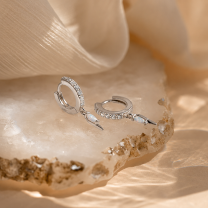 Silver hoop earrings with small stones on a seashell